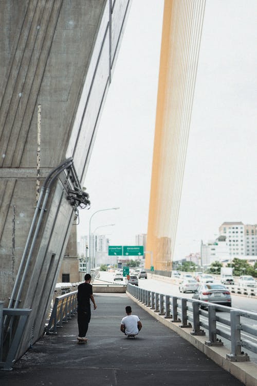不可识别的运动员周末在城市桥梁上滑板 · 免费素材图片