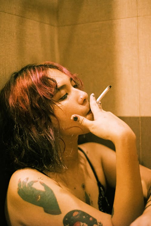 靠在墙上吸烟的女人 · 免费素材图片