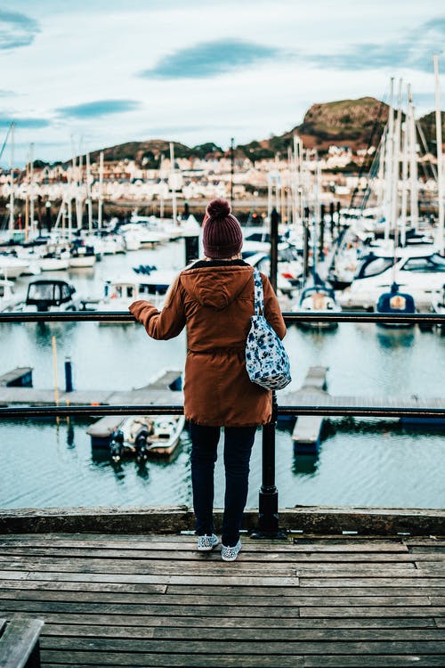 棕色连帽外套夹克站在码头上的人 · 免费素材图片
