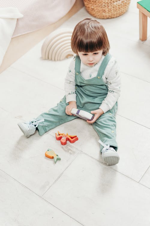 一个孩子坐在地板上的玩具 · 免费素材图片