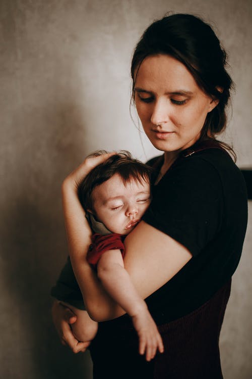 母亲抱着她可爱的熟睡婴儿 · 免费素材图片