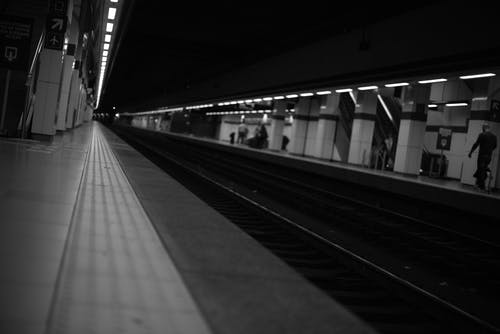 在火车站灰度摄影上行走的人 · 免费素材图片