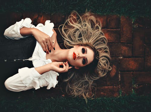 躺在人行道上绿草附近的女人 · 免费素材图片