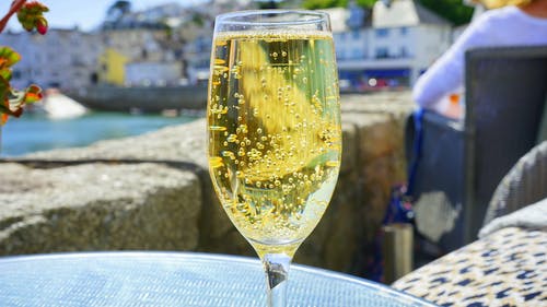 透明的香槟杯，蓝色玻璃圆桌上的黄色液体 · 免费素材图片