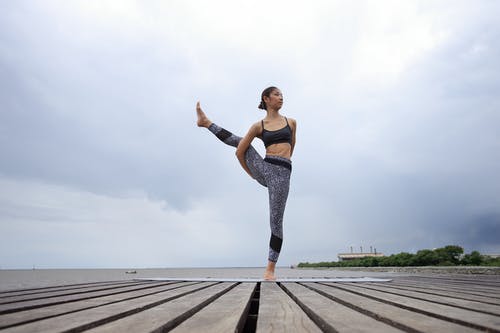 黑色和白色紧身裤，站在木码头的一条腿上的女人 · 免费素材图片