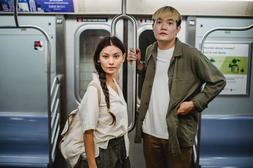 时髦的年轻亚洲夫妇，乘地铁上下班时按住扶手 · 免费素材图片