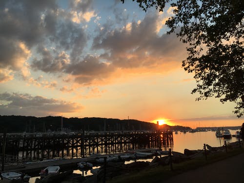 日落期间水体上的棕色木码头 · 免费素材图片