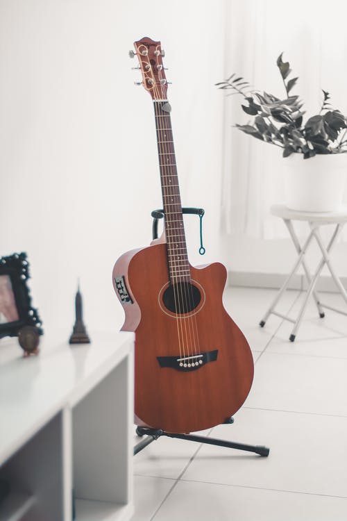 黑色吉他架子上的棕色原声吉他 · 免费素材图片