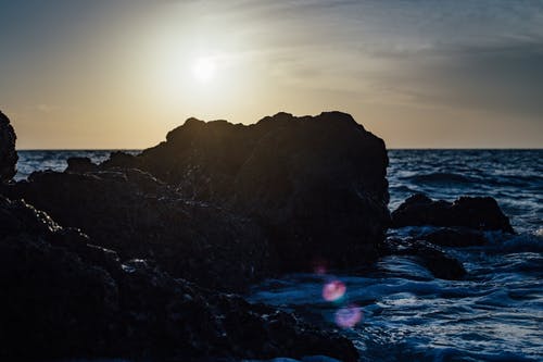 日落期间在海边黑石头 · 免费素材图片