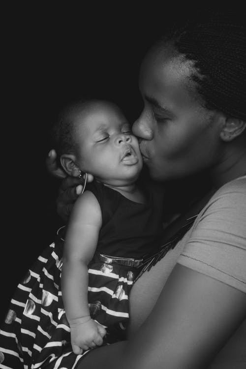 母亲亲吻婴儿的灰度照片 · 免费素材图片