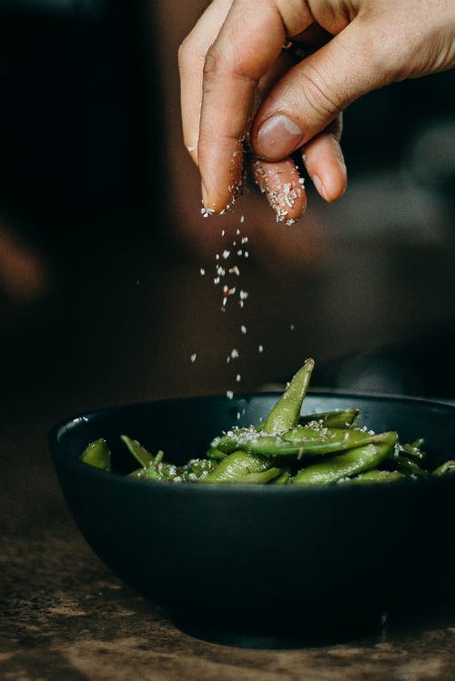 人在碗上的青豆上浇调味料 · 免费素材图片