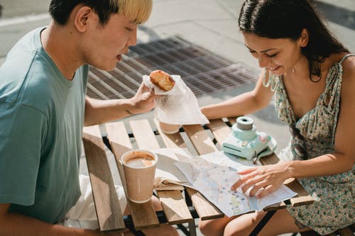 不同的夫妇在探索地图时在咖啡馆吃早餐 · 免费素材图片