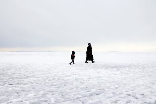 两人在积雪的地面上行走 · 免费素材图片