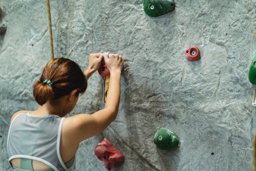 爬在灰色的墙上的年轻女子 · 免费素材图片