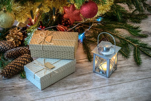 在礼品盒和圣诞树旁边的灯笼内点燃蜡烛 · 免费素材图片