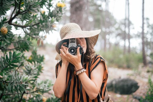 戴棕色太阳帽子拿着照相机的妇女 · 免费素材图片