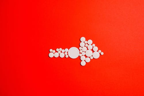 红色表面上的白色圆形药丸 · 免费素材图片
