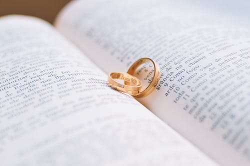 书页上的两个金色结婚戒指 · 免费素材图片