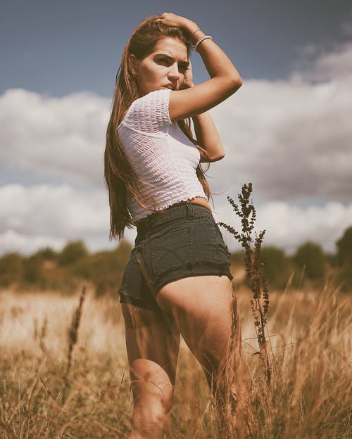 女人穿着黑色短裤摸她的头的浅焦点照片 · 免费素材图片