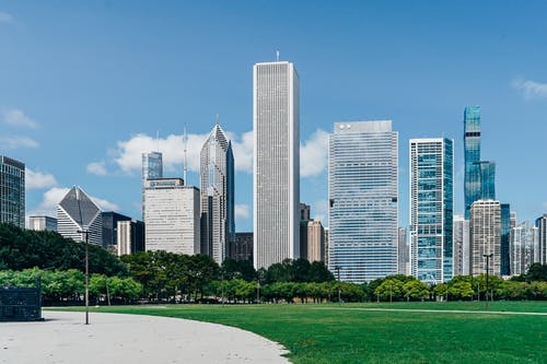 现代市区与绿色草坪附近的摩天大楼 · 免费素材图片
