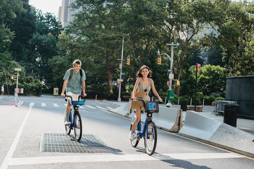 性格开朗的夫妇在空荡荡的街道上骑自行车 · 免费素材图片