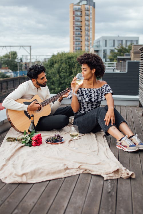 男人和女人在玩吉他时坐在长椅上 · 免费素材图片