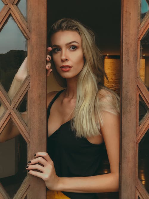 在棕色的木质门上偷看的女人 · 免费素材图片
