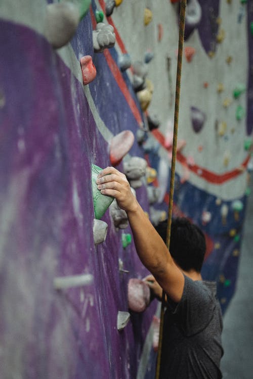 匿名登山者在健身房练习抱石 · 免费素材图片