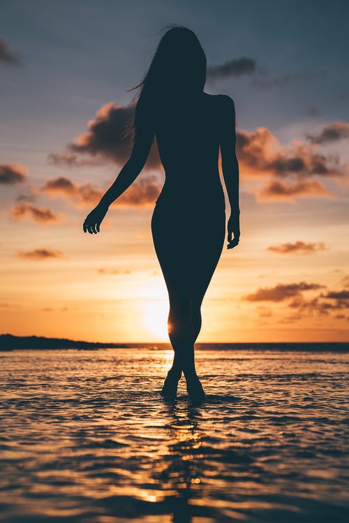 人在日落时站在海滩上的剪影 · 免费素材图片