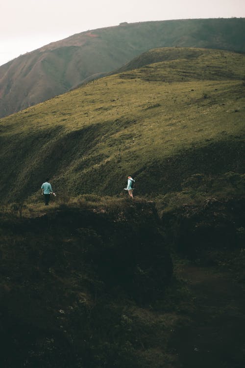 2个人站在山附近的绿草地上 · 免费素材图片