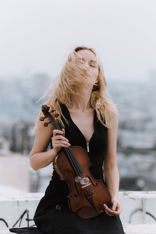 小提琴站在屋顶上的女人 · 免费素材图片