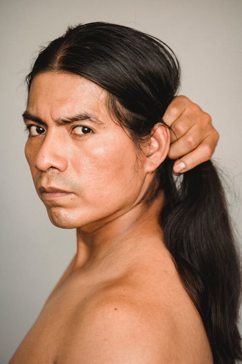 严重的美洲印第安人触摸头发，看着相机 · 免费素材图片