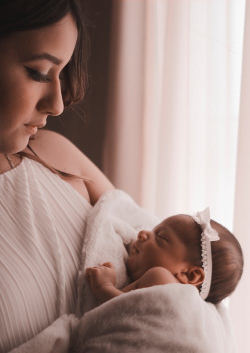 女人抱着她可爱的婴儿的选择性聚焦摄影 · 免费素材图片