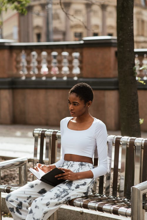 梦幻般的黑人妇女，与城市的长凳上休息的书 · 免费素材图片