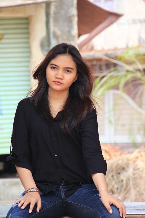 有关咖啡色头发的女人, 坐, 牛仔裤的免费素材图片