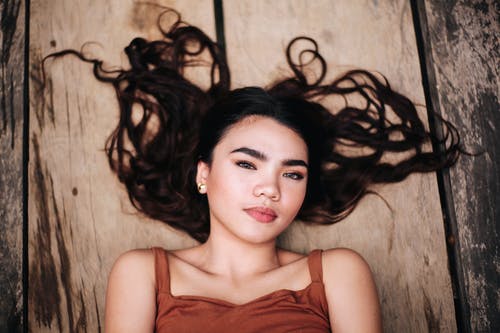 躺在木质表面上的女人的照片 · 免费素材图片