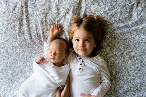 婴儿睡在女孩旁边灰色花卉纺织 · 免费素材图片