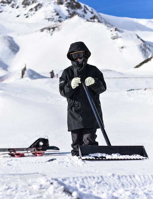 使用雪铲穿雪服的人的选择性聚焦摄影 · 免费素材图片