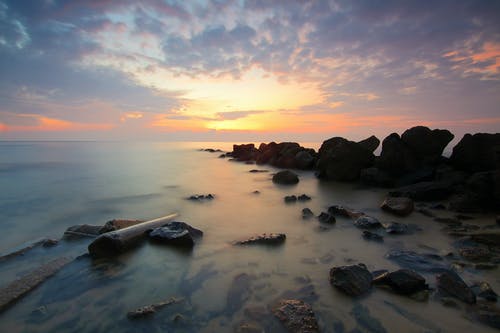日落期间海上黑岩形成 · 免费素材图片