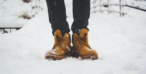 穿着双棕色皮靴的人踩在雪地上 · 免费素材图片