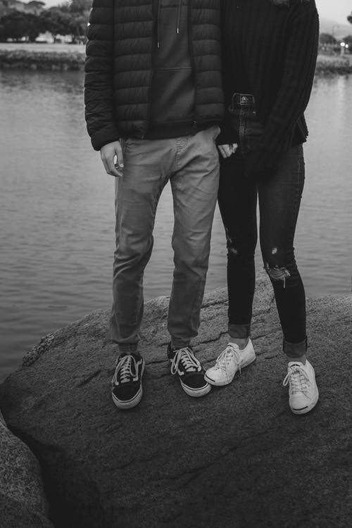 无法认出的浪漫情侣拥抱，而站在湖岸上的石头上 · 免费素材图片