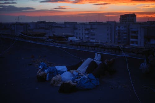 妇女在日落时躺在建筑物的屋顶上 · 免费素材图片