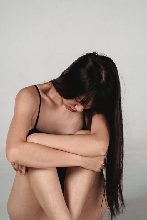 诱人的年轻亚洲女性拥抱膝盖在工作室 · 免费素材图片