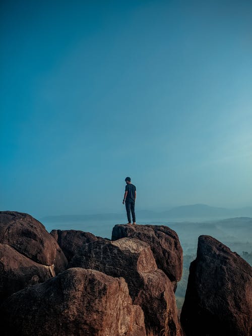 男子站在棕色岩层上 · 免费素材图片