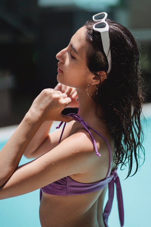 有魅力的女人在游泳池中放松和抚摸泳装胸罩皮带 · 免费素材图片