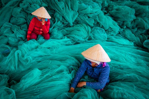 两名妇女被绿色鱼网包围 · 免费素材图片