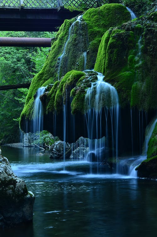 苔藓岩层中的瀑布的延时照片 · 免费素材图片