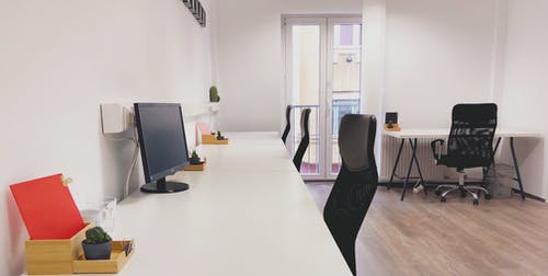 在白色木桌旁边的黑办公室卷椅 · 免费素材图片