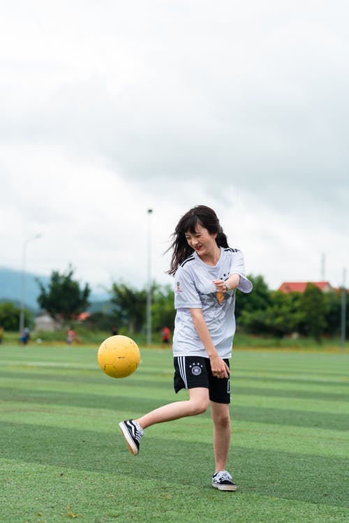 白衬衫和黑色短裤踢足球的女人 · 免费素材图片