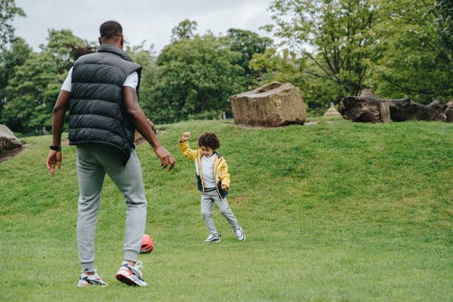 顽皮的黑人男孩和父亲踢足球 · 免费素材图片